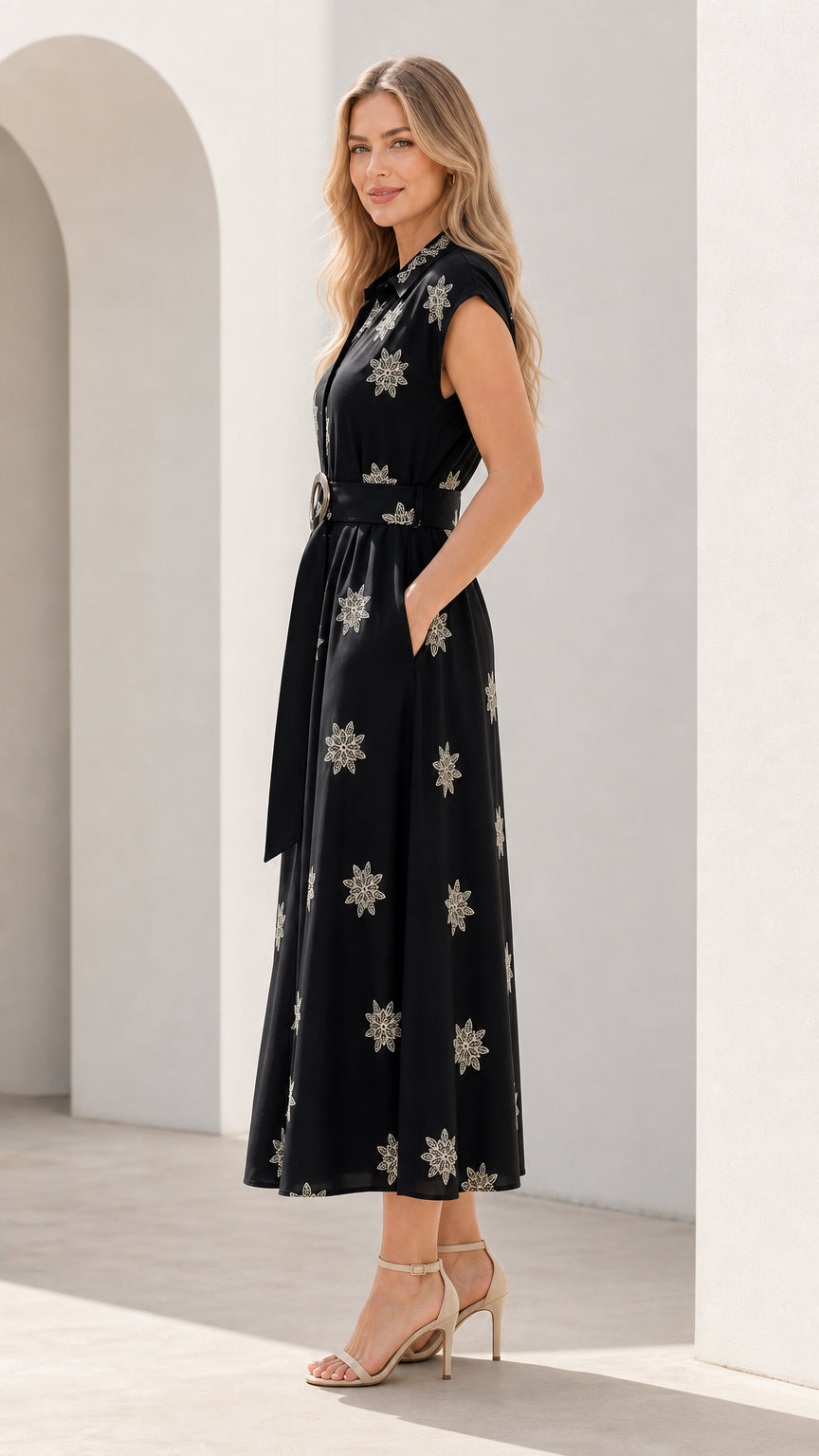 Side profile of woman wearing black floral embroidered midi dress with side pockets