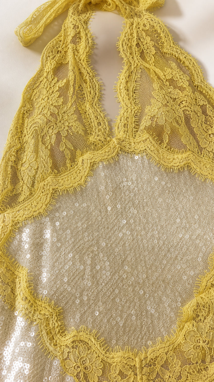 Close-up detail of yellow floral lace trim and shimmering sequins