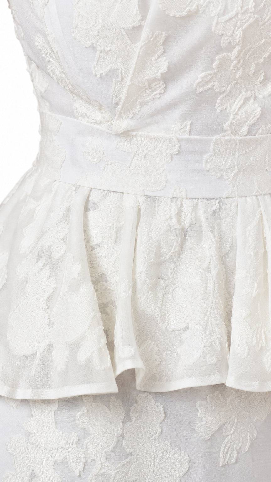 Close-up detail of white floral jacquard fabric and peplum waist seam