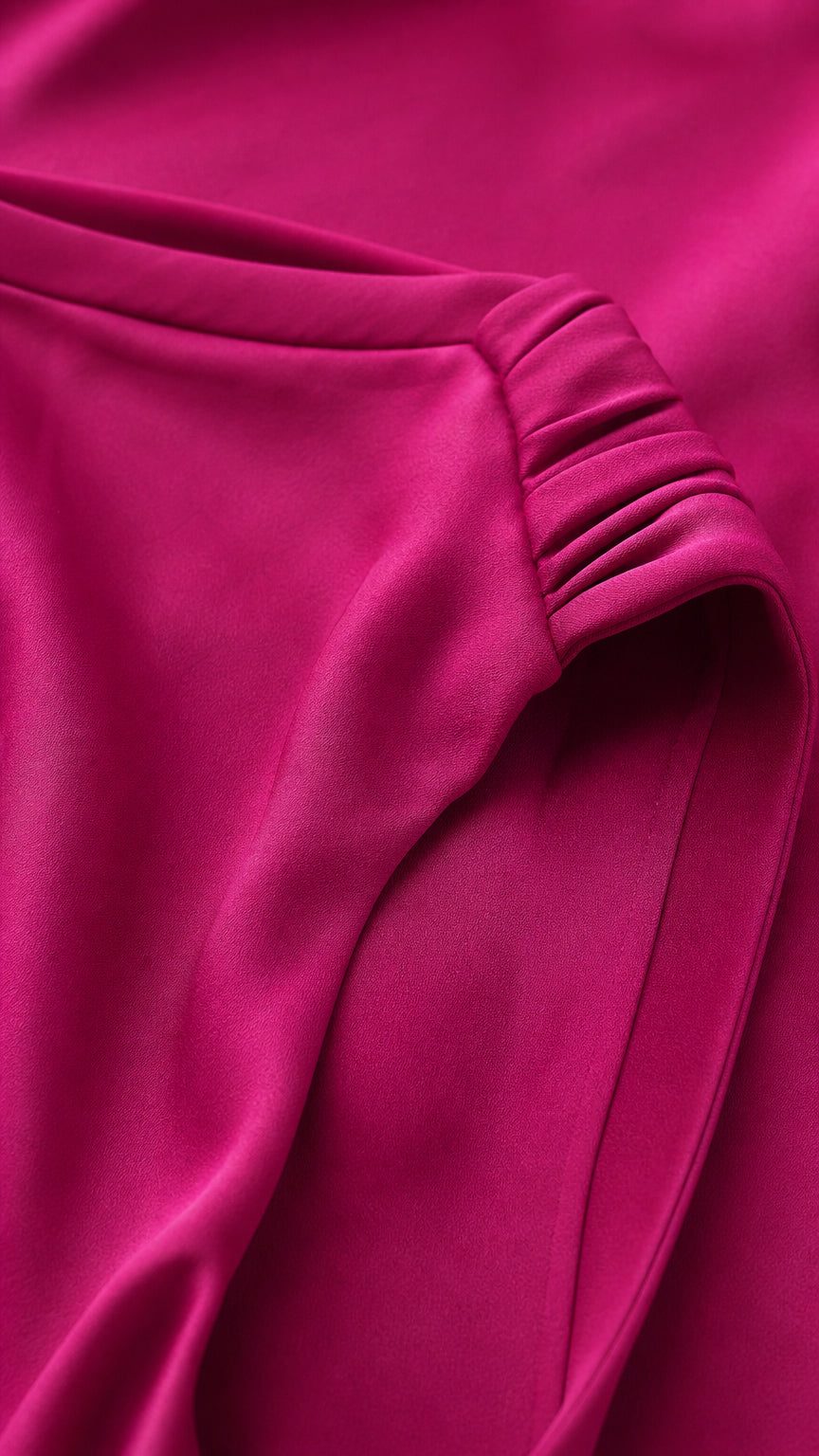 Close-up detail of pleated shoulder gathering and fabric texture on fuchsia gown