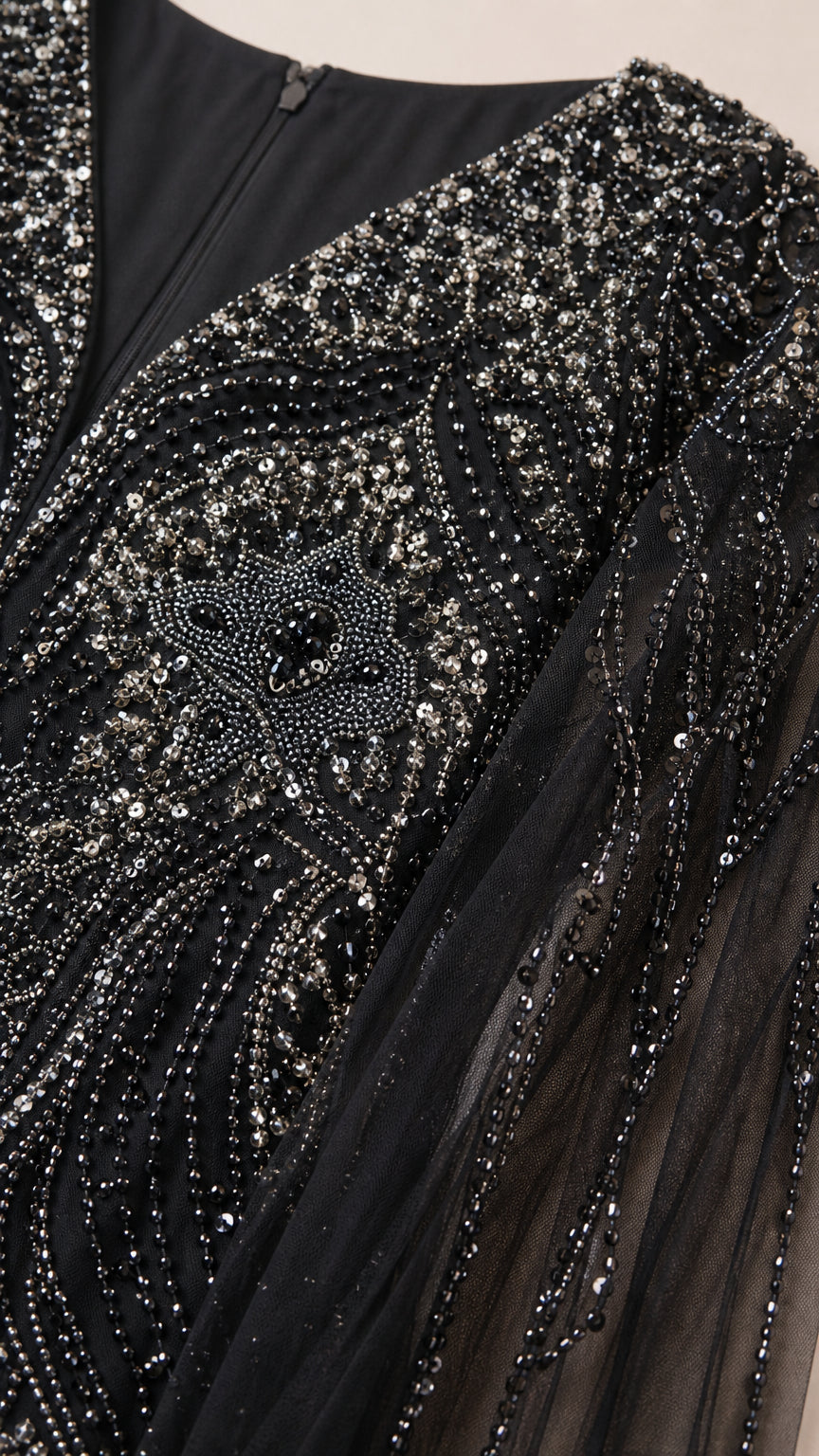Close-up detail of intricate silver and black sequin embroidery on mesh fabric