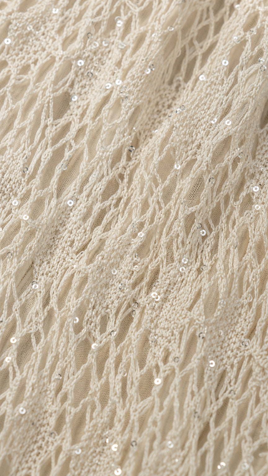 Close-up detail of textured open-knit lace fabric with shimmering sequins