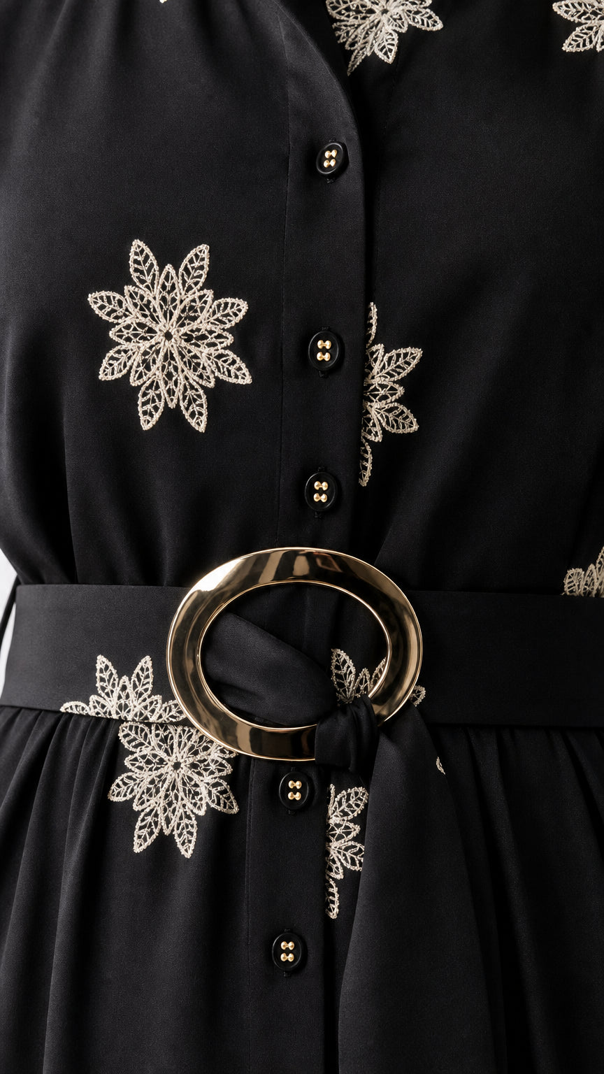 Close-up detail of floral embroidery and metallic ring belt on black shirt dress