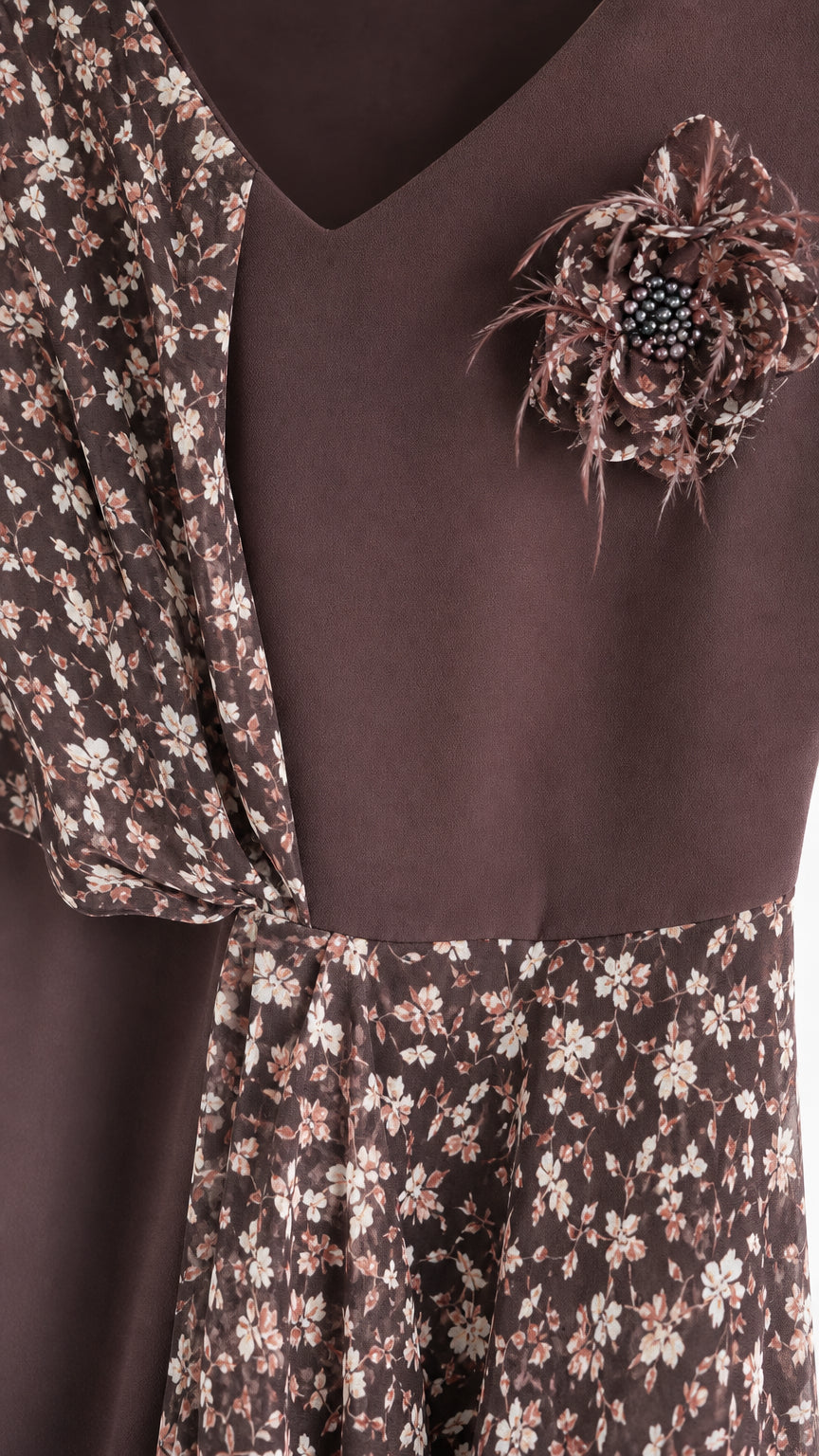 Close up of V-neckline with 3D floral brooch accent and draped sleeve