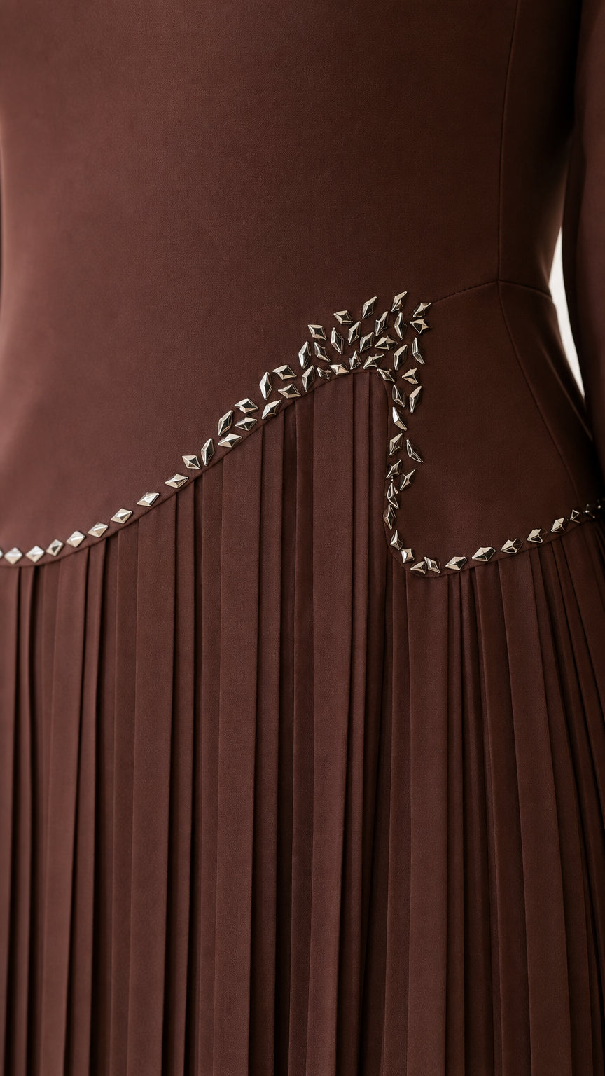 Close-up detail of the rhinestone embellishment and accordion pleats on the brown dress