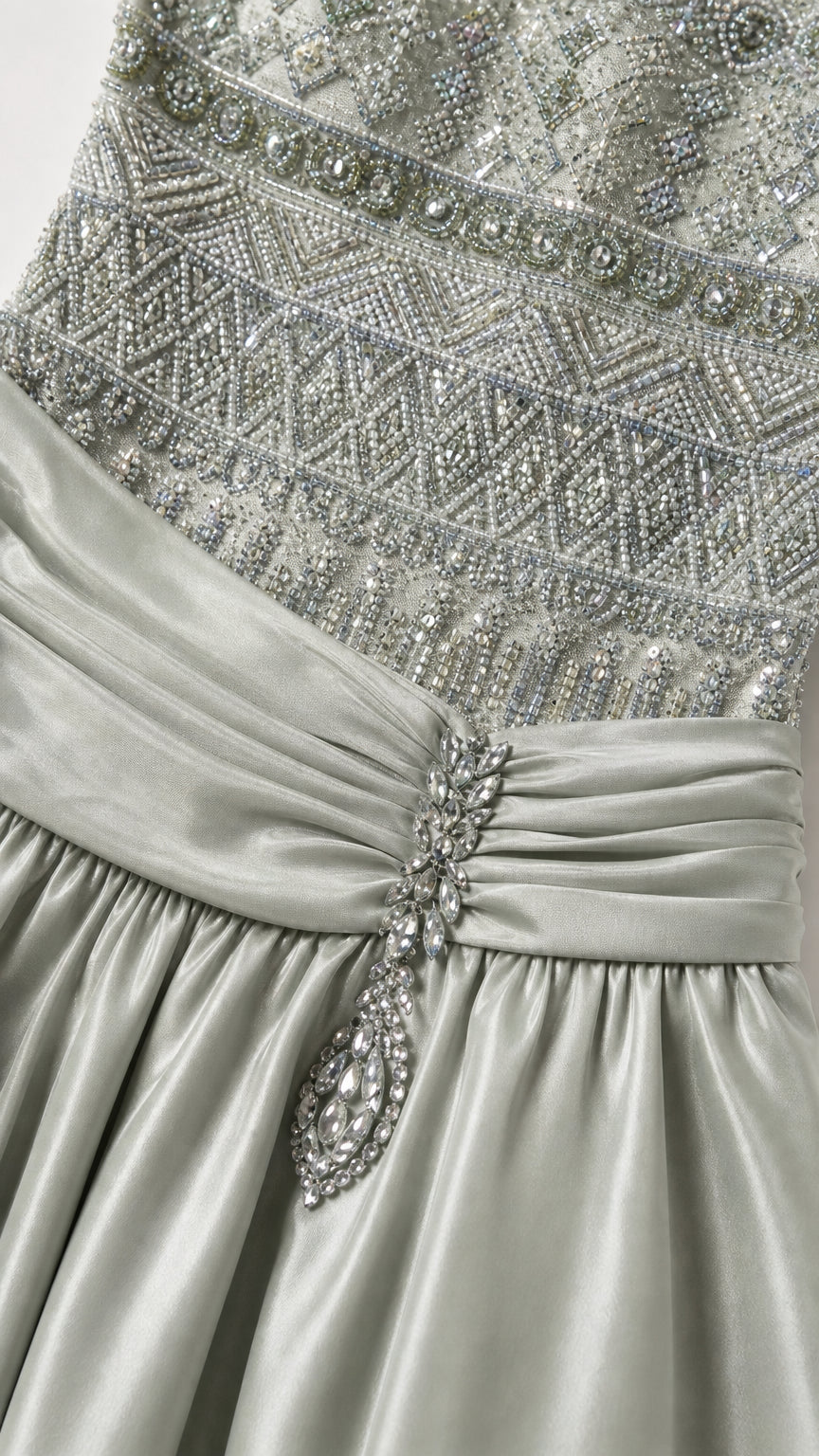 Close-up detail of intricate beadwork, pleated waist, and crystal brooch accent