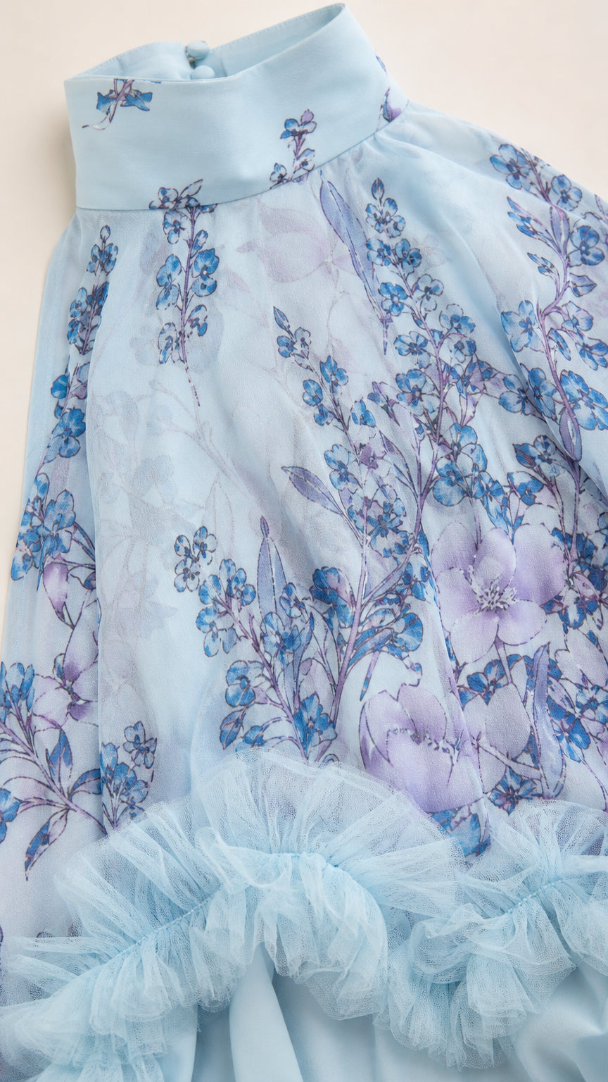 Close-up detail of high halter neckline and ruffled mesh trim on light blue floral fabric