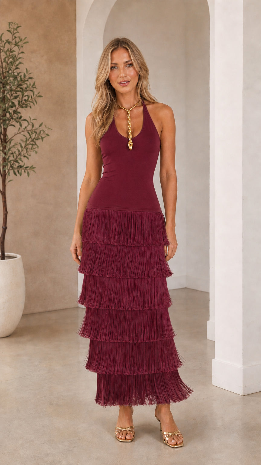 Front view of woman wearing deep burgundy tiered fringe halter maxi dress